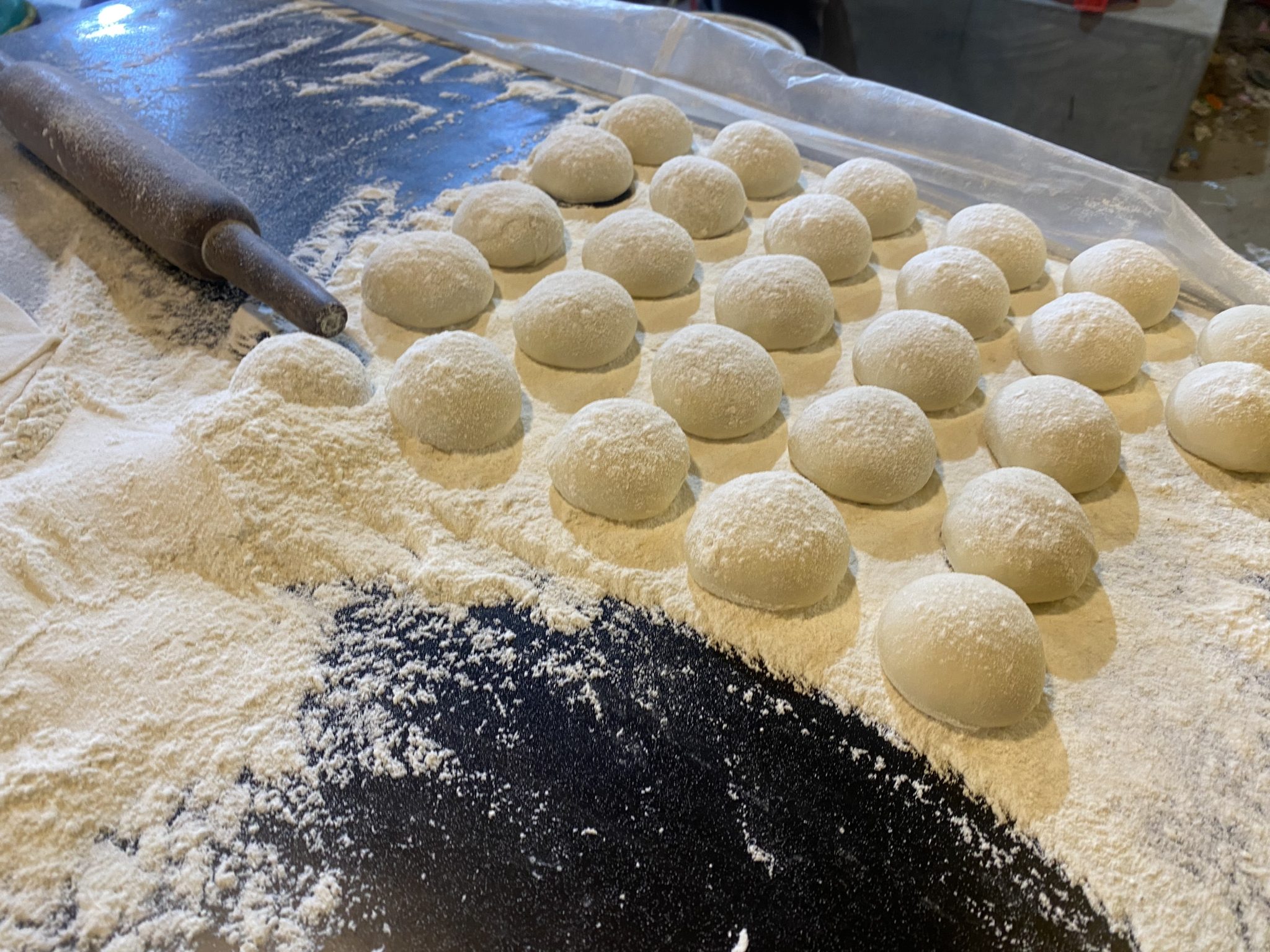 Round balls of dough covered in flour, set out in rows.